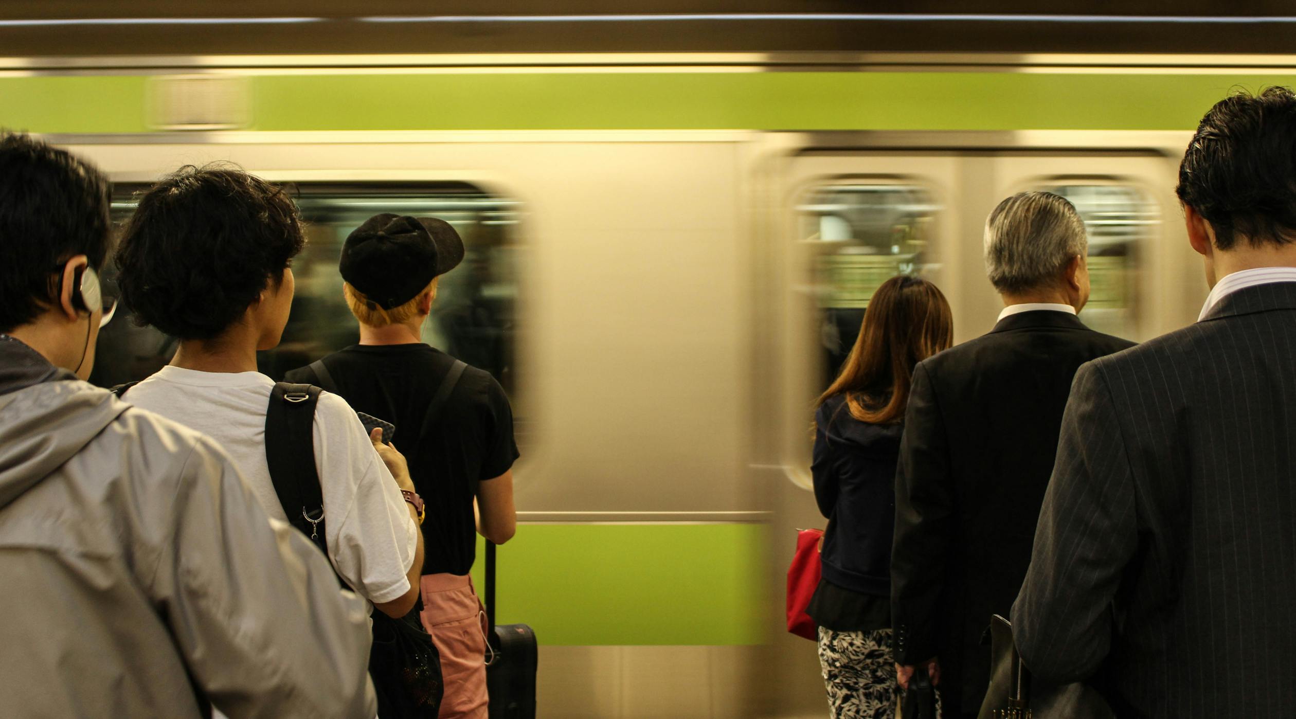 Passengers at a Japanese train station platform as a train pulls in - daily commute scene