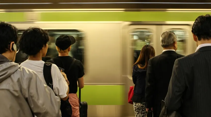 Passengers at a Japanese train station platform as a train pulls in - daily commute scene